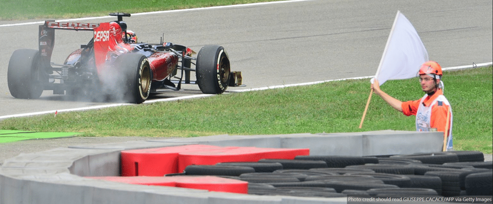 Marshal holding a white flag as an F1 car passes
