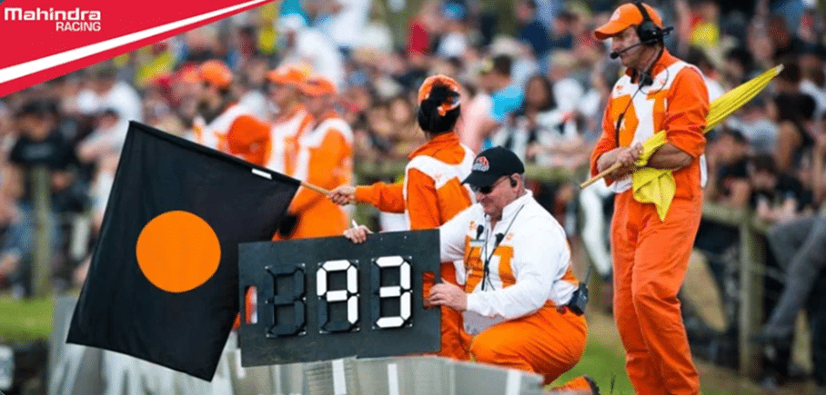 Black flag with orange circle shown with a car number