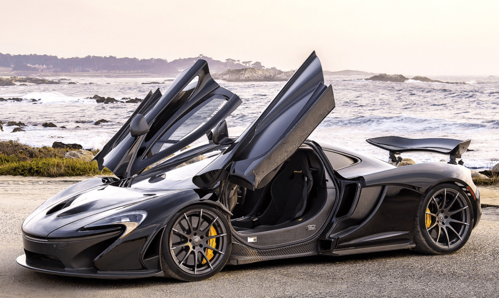 McLaren P1 with dihedral doors open by the coast