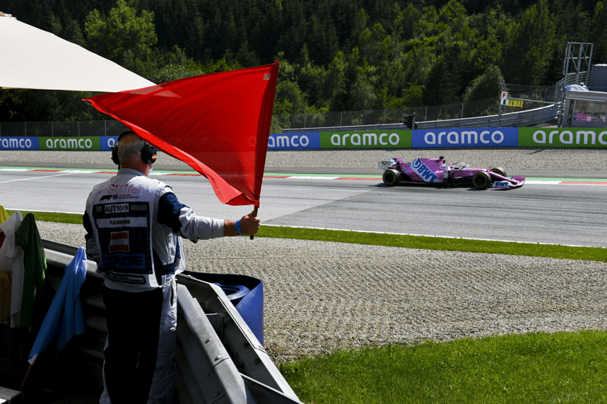 Marshal holding a red flag as a racing car passes