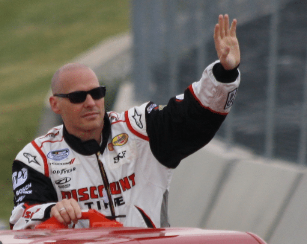 Jacques Villeneuve waving from a car in white racing suit