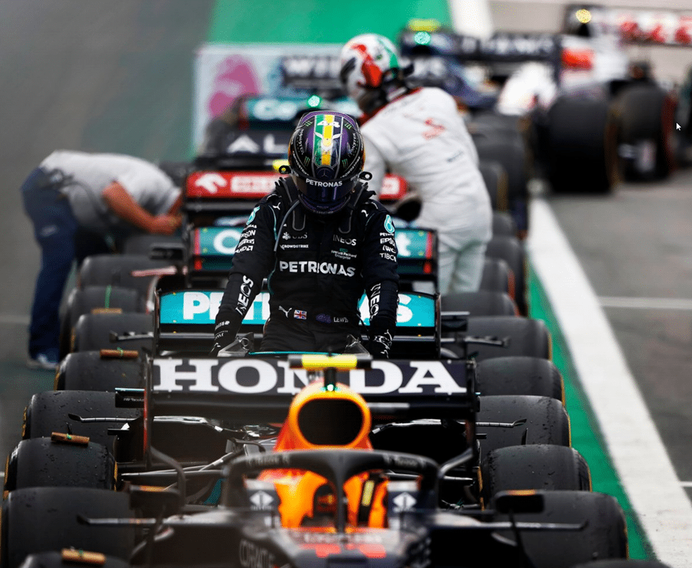 F1 cars parked in parc fermé with mechanics gathered around them