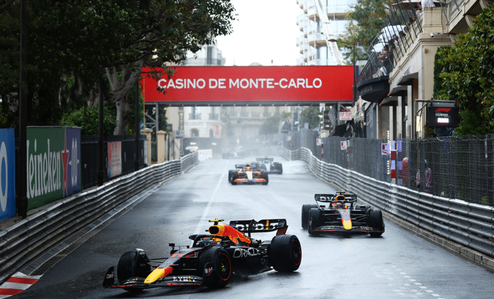 F1 cars racing through wet Monaco streets in rainy conditions