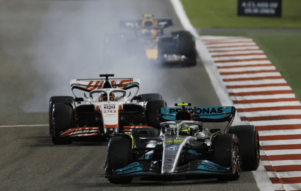 Mercedes F1 car weaving on track ahead of a Haas during an out lap