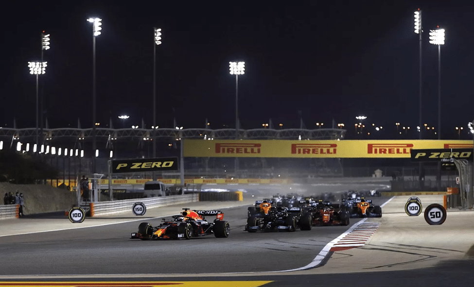 Multiple F1 cars racing side-by-side at night in Bahrain