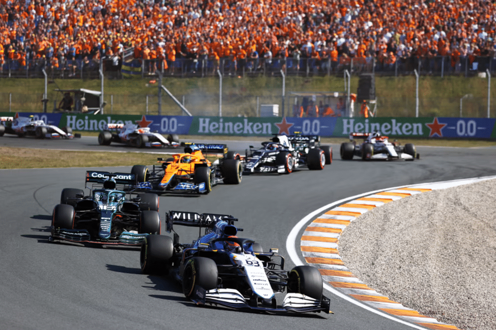 F1 cars racing side by side at race start with orange crowd
