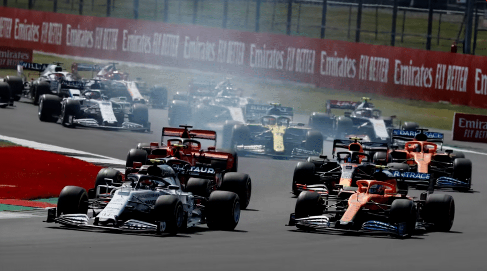 Multiple F1 cars battling through a corner at race start