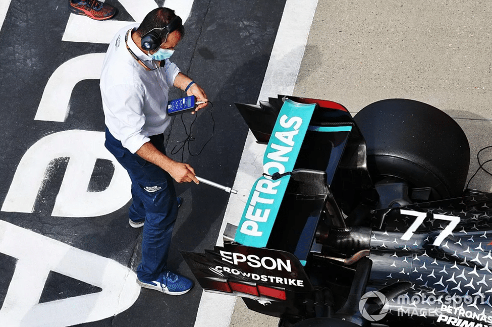 Mechanic inspecting a Mercedes F1 car in the pit lane